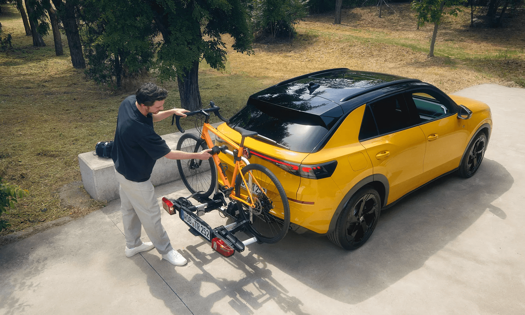 Vīrietis uzstāda oranžu velosipēdu uz Volkswagen T-Roc sakabes.