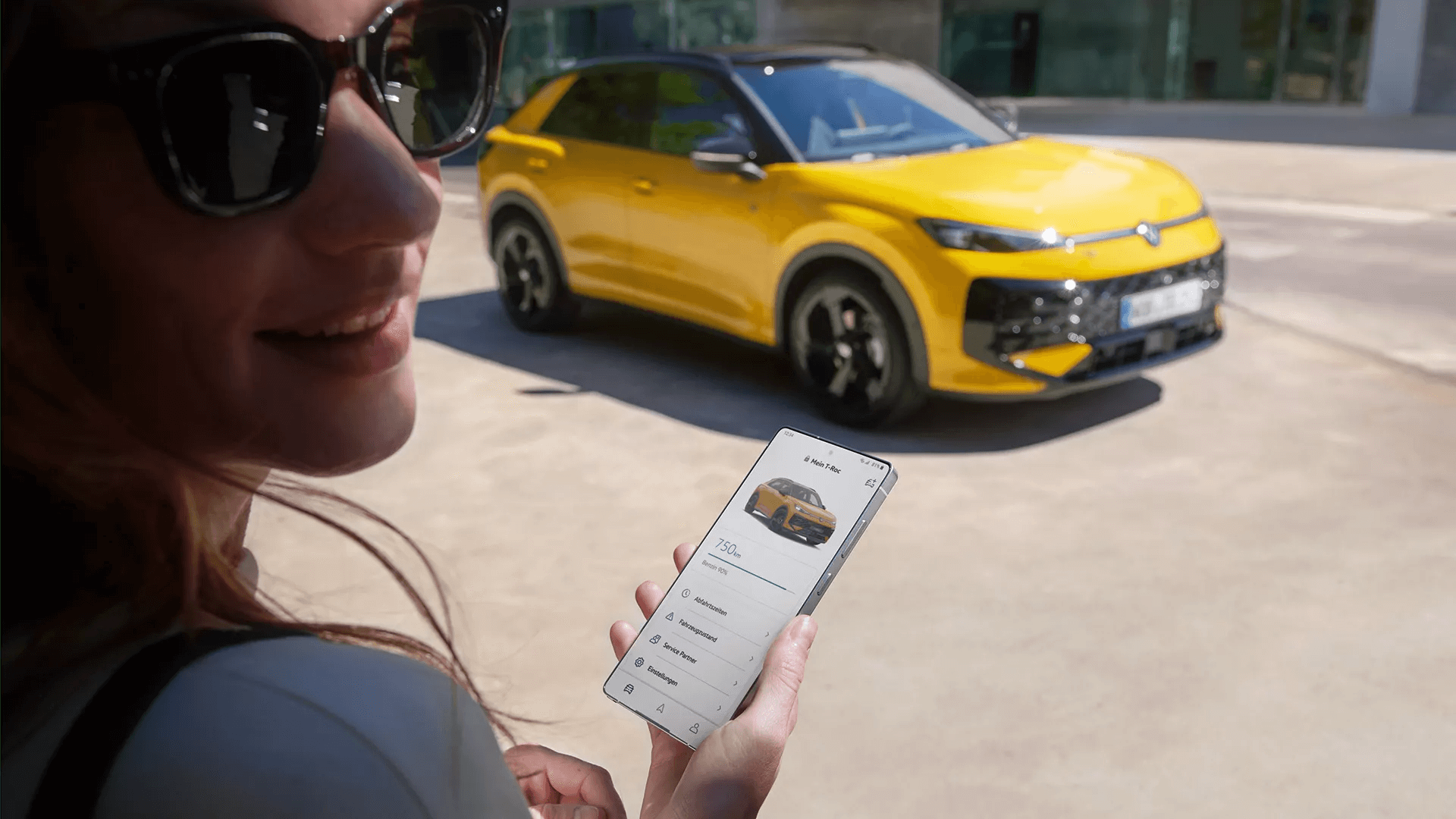 Sieviete izmanto viedtālruni, lai pārbaudītu savienoto Volkswagen T-Roc.