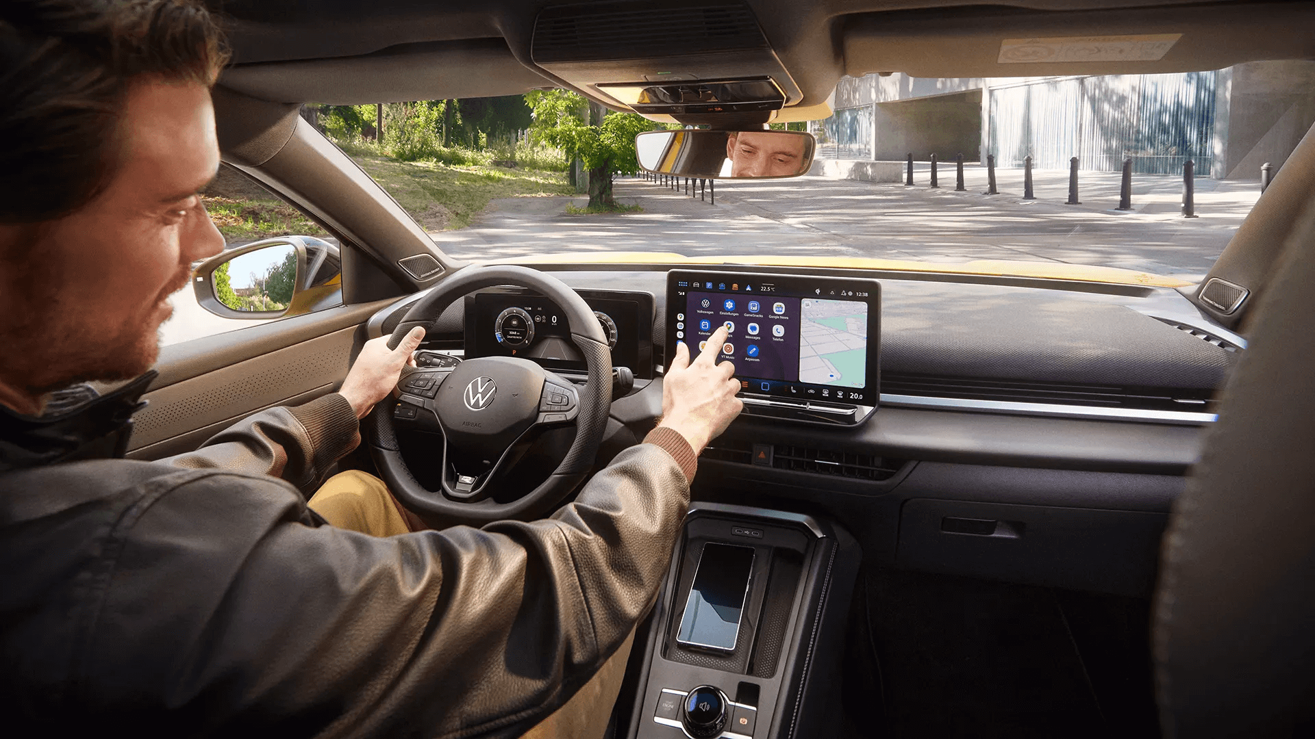 Vīrietis izmanto Volkswagen T-Roc centrālo ekrānu ar navigācijas un lietotņu izvēlni.